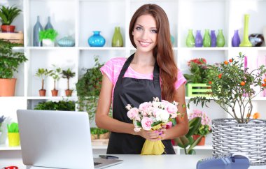 Beautiful girl florist with flowers in flowers shop clipart