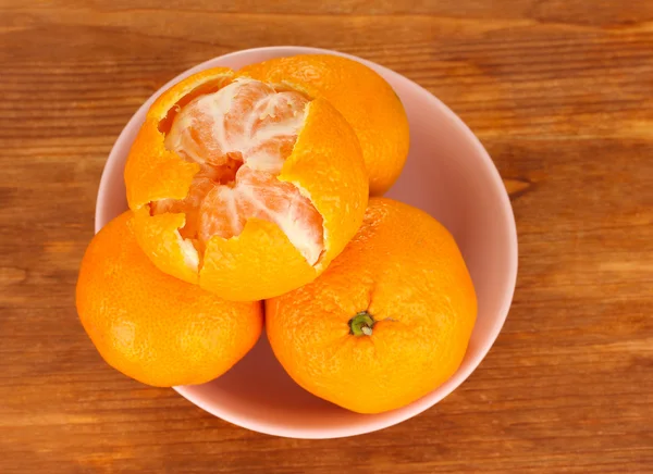 Tasty mandarines in color bowl on wooden background — Stock Photo, Image