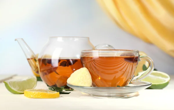 Vattenkokare och kopp te med ingefära på träbord på ljus bakgrund — Stockfoto