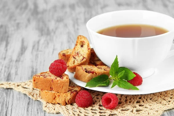 Cup of tea with cookies and raspberries on table close-up