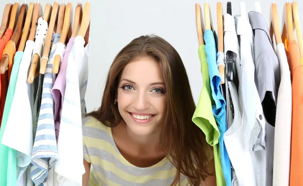 Mooie jonge vrouw in de buurt van rack met hangers — Stockfoto