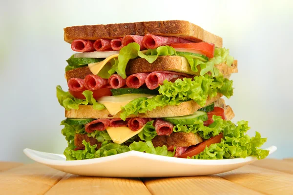 Величезний бутерброд на дерев'яному столі, на світлому фоні — стокове фото