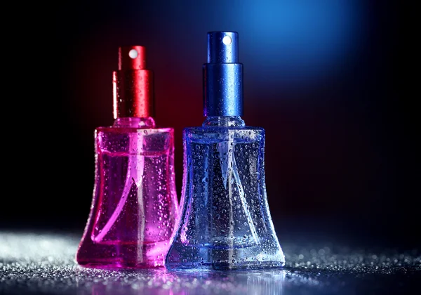 Perempuan parfum dalam botol indah di latar belakang gelap dengan cahaya warna — Stok Foto