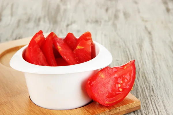 El tomate fresco brillante cortan los trozos en la escudilla a la mesa de madera de cerca —  Fotos de Stock