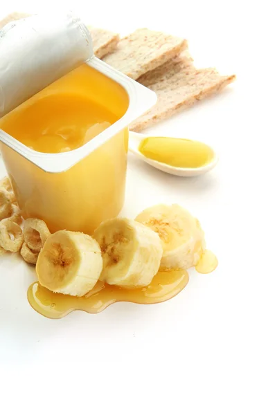 Dessert savoureux dans une tasse ouverte en plastique et banane, isolé sur blanc — Photo