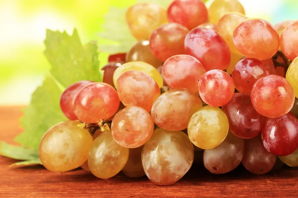 Dojrzałe słodkie winogrona na drewnianym stole, na tle przyrody — Zdjęcie stockowe