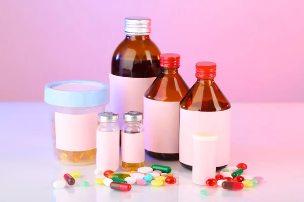 Pills and medicine bottles on pink background — Stock Photo, Image