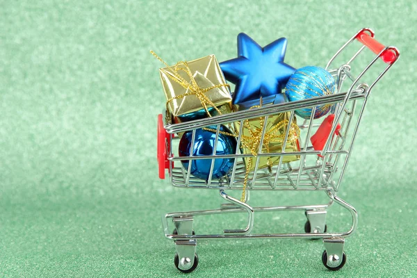 Christmas gifts in shopping trolley, on green shiny background — Stock Photo, Image