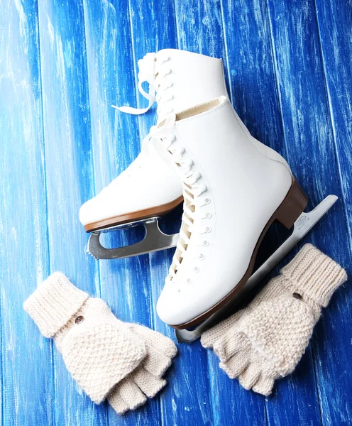 Wool fingerless gloves and skates for figure skating, on wooden background — Stock Photo, Image