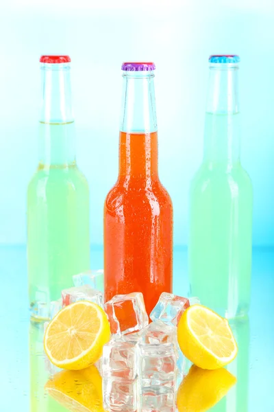 Drycker i glasflaskor med isbitar på blå bakgrund — Stockfoto