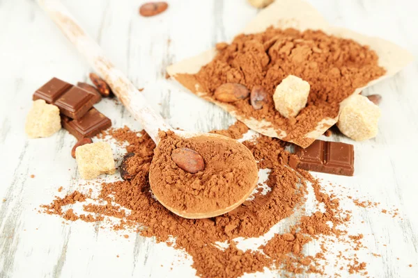 Cocoa powder in spoon on wooden table — Stock Photo, Image