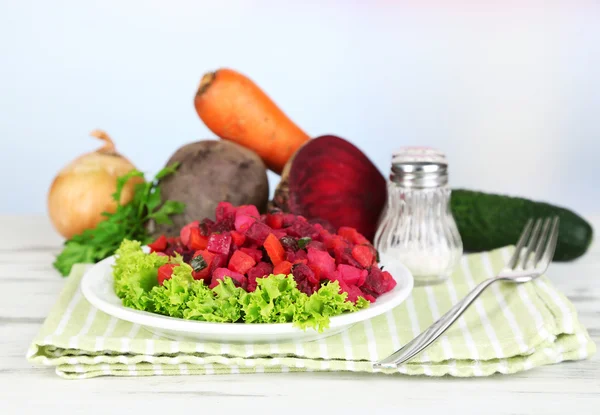 Rübensalat auf Teller auf Serviette auf Holztisch auf hellem Hintergrund — Stockfoto