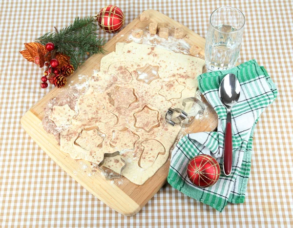 Fazer biscoitos de Natal na placa de madeira no fundo da toalha de mesa — Fotografia de Stock