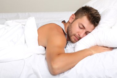 Yakışıklı genç adam yatakta.