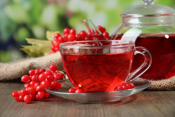 Still life with viburnum tea on sackcloth napkin, on wooden background — Stock Photo, Image