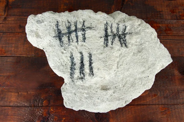 Counting days by drawing sticks on stone on wooden background — Stock Photo, Image