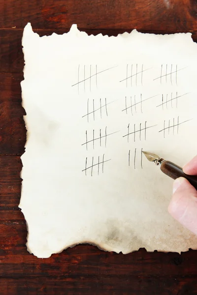 Counting days by drawing sticks on paper on wooden background — Stock Photo, Image