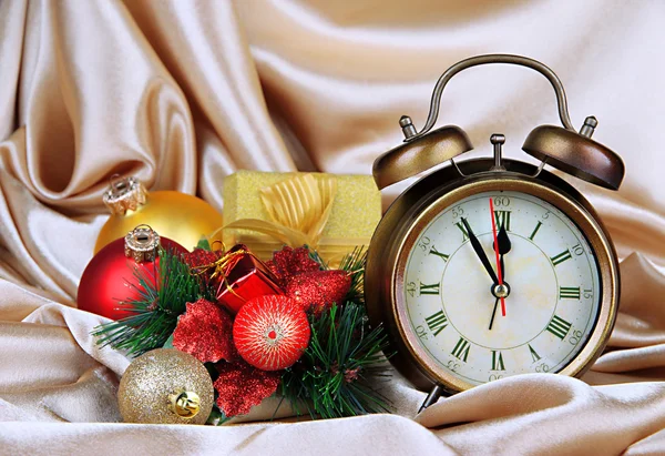 Wecker mit Weihnachtsdekoration auf goldenem Stoff Hintergrund — Stockfoto