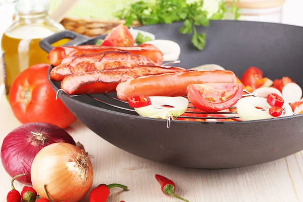 Delicious sausages with vegetables in wok on wooden table close-up — Stock Photo, Image