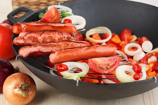 Leckere Würstchen mit Gemüse im Wok auf Holztisch in Großaufnahme — Stockfoto