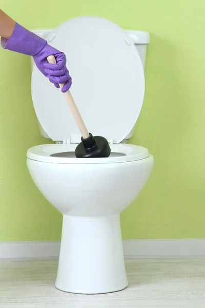 Frau benutzt Kolben, um Toilettenschüssel im Badezimmer zu entstopfen — Stockfoto