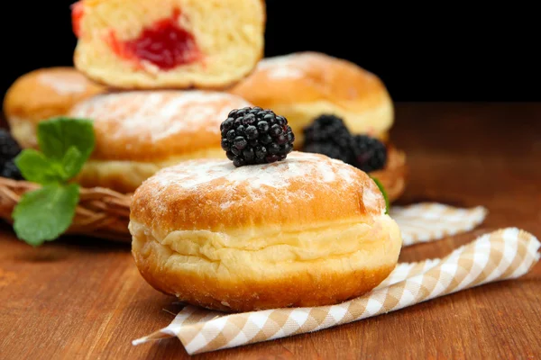 Tasty donuts with berries on wooden table — Stock Photo, Image