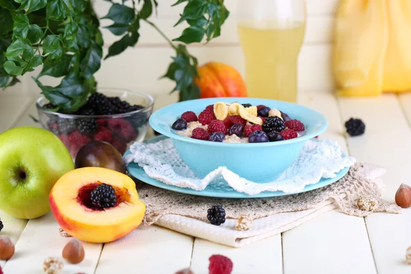 Oatmeal in plate with berries on napkins on wooden table on bright background — Stock Photo, Image