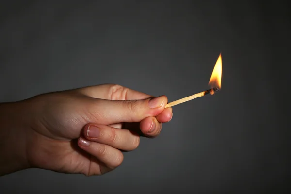 Brinnande tändsticka i handen på svart bakgrund — Stockfoto