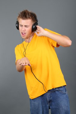 yakışıklı genç adam gri arka planda müzik dinlemek