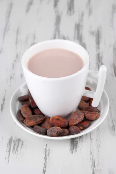 Cocoa drink and cocoa beans on wooden background — Stock Photo, Image