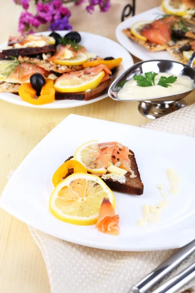 Salmon sandwiches on plate on wooden table close-up — Stock Photo, Image