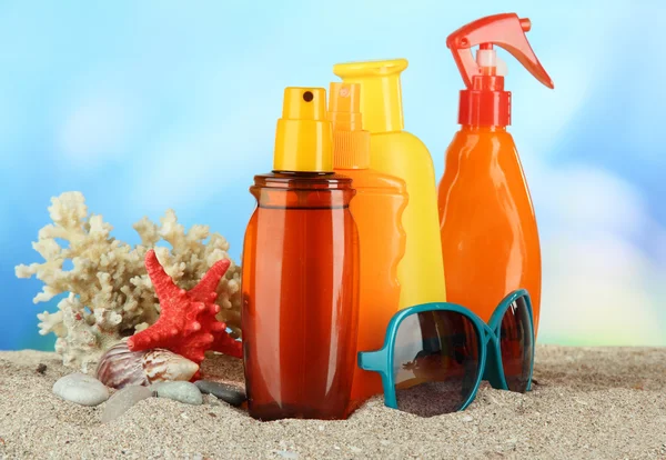 Бутылки с кремом для загара и солнцезащитными очками, на синем фоне — стоковое фото