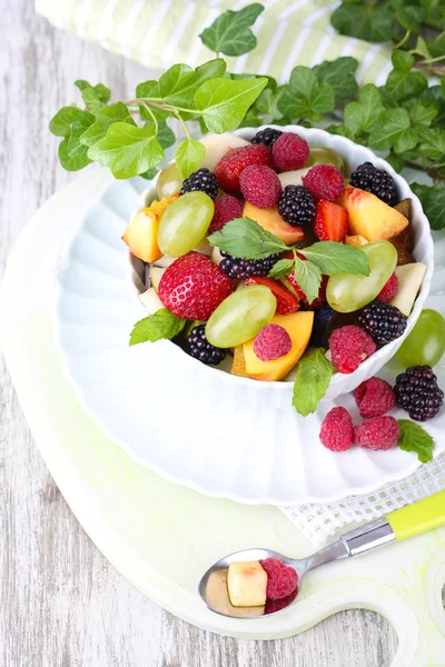 Salada de frutas em tigela, em fundo de mesa de madeira — Fotografia de Stock