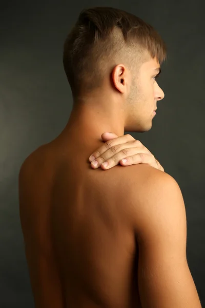 Young man with neck pain on grey background — Stock Photo, Image