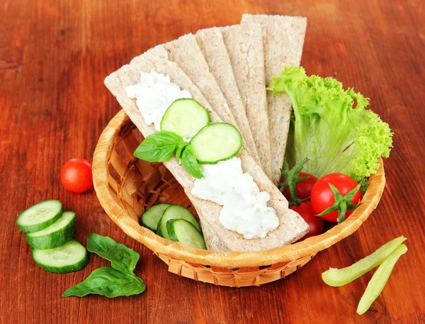 Tasty crispbreads with vegetables on wooden background — Stock Photo, Image