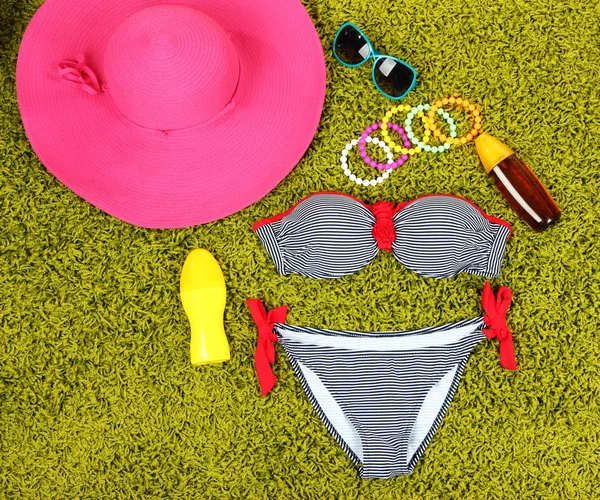 Swimsuit and beach items on green background — Stock Photo, Image