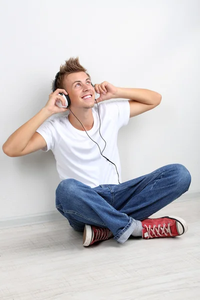 Handsome young man listening to music on grey background — Stock Photo, Image