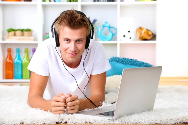 Genç adam laptop ile halı üzerinde rahatlatıcı — Stok fotoğraf