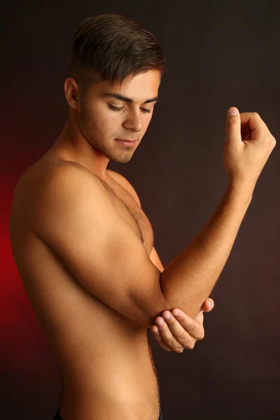 Mladý muž s bolestí rukou na tmavém pozadí — Stock fotografie