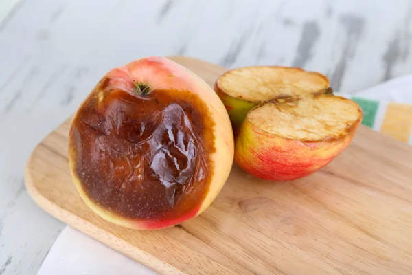 Pommes pourries sur planche de bois sur table — Photo