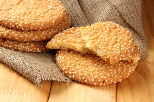 Galletas caseras con semillas de sésamo, sobre mesa de madera, sobre fondo de saco — Foto de Stock