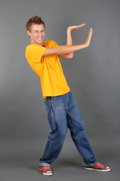 Schöner junger Mann tanzt auf grauem Hintergrund — Stockfoto