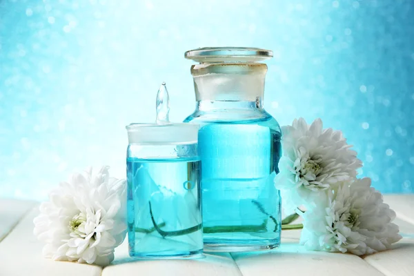 Botellas de vidrio con esencia de color, sobre mesa de madera, sobre fondo azul —  Fotos de Stock