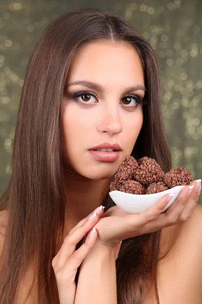 Portrait of beautiful young girl with chocolate candy on shiny background — Stock Photo, Image