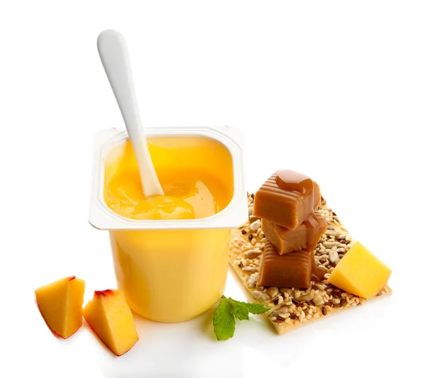 Sabroso yogur con trozos de fruta fresca, galletas y caramelos de caramelo aislados en blanco —  Fotos de Stock