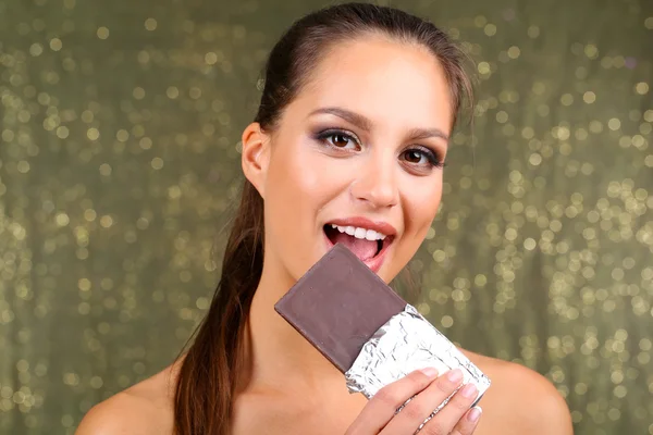 Portrait of beautiful young girl with chocolate on shiny background — Stock Photo, Image