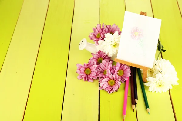 Composición de flores y caballete pequeño con cuadro sobre mesa de madera de primer plano — Foto de Stock