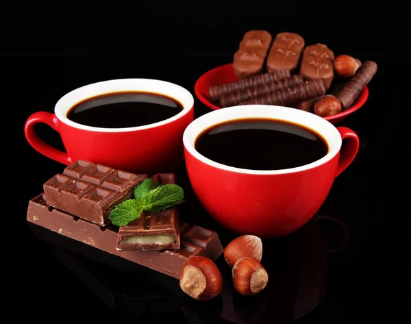 Rode kopjes sterke koffie en chocolade bars geïsoleerd op zwart — Stockfoto