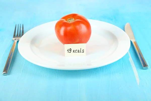 Calorie content of tomato on plate on wooden table close-up — Stock Photo, Image