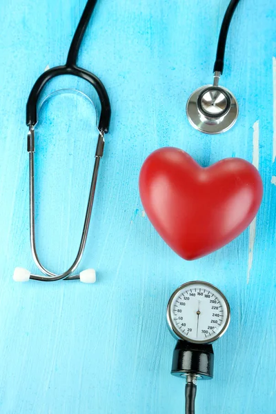 Tonometer, stethoscope and heart on wooden table close-up — Stock Photo, Image